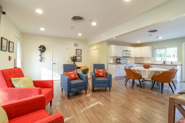A inviting common area with red and blue chairs and a dining table.