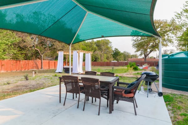 Patio with seating and grill under shade at Austin Gardens Senior Living