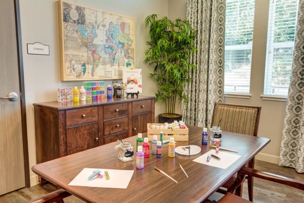 A well-equipped art room featuring painting supplies on a table with a world map on the wall.