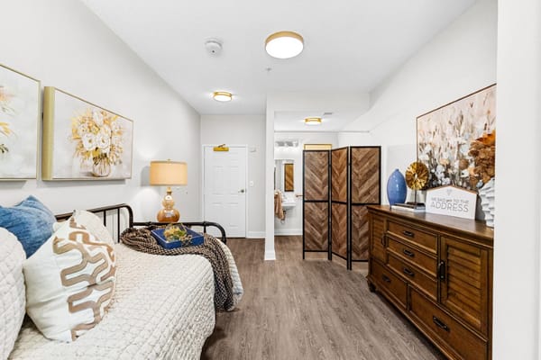 A stylish bedroom featuring a bed, a dresser, and decorative art.