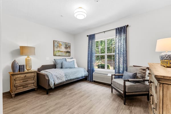 Light-filled bedroom with a single bed, chair, and window view.