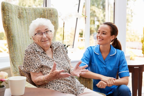 Elderly resident with caregiver smiling in a sunny room