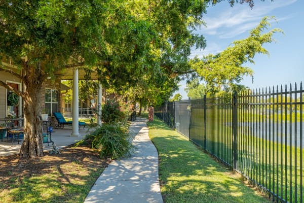 Pathway lined with trees and flowers at Laurel Springs senior living facility.