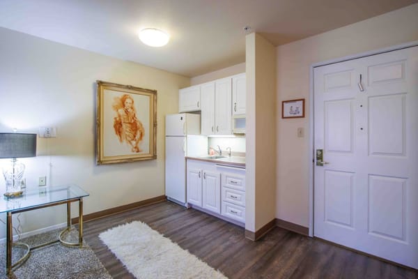 Interior view of a living space featuring a kitchenette and decorative artwork.