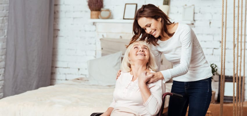 A caregiver assisting a smiling resident in a cozy room