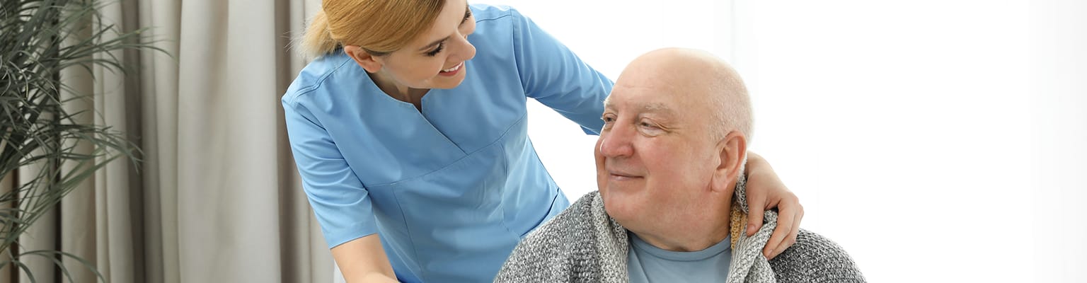 Caregiver assisting an elderly resident in a well-lit room
