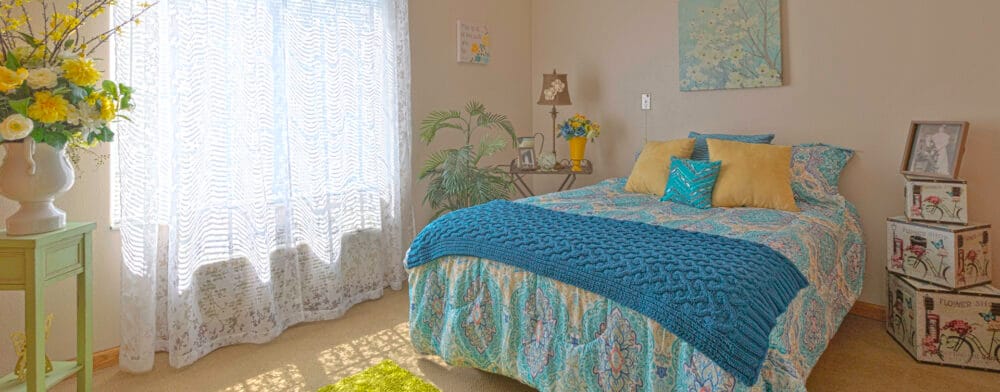 Brightly decorated resident room with a bed and plants