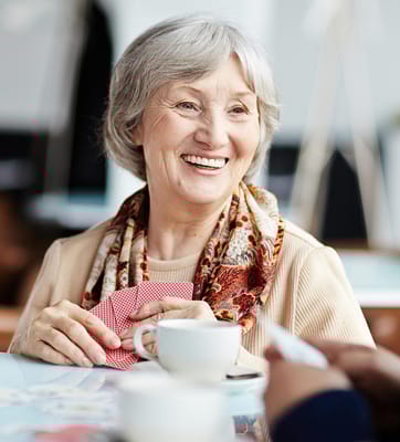 Senior woman enjoying a card game with a cup of coffee