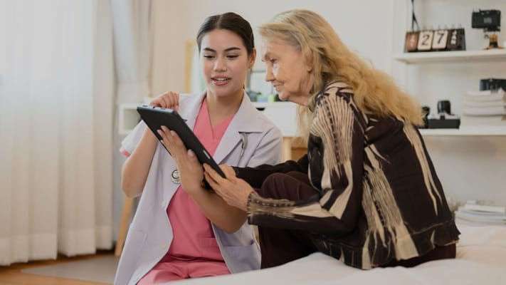 Nurse assisting resident with a tablet in a cozy room