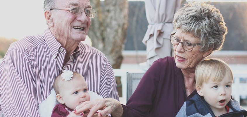 Elderly couple enjoying time with grandchildren outdoors