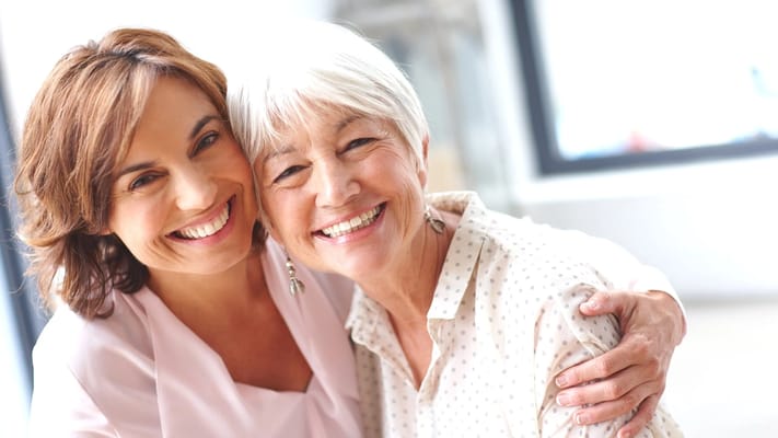 Two women smiling together in a bright environment