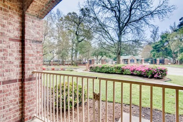 View from a balcony overlooking landscaped grounds with flowers and trees