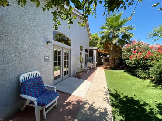 A sunny outdoor patio with chairs and greenery