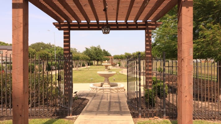 Pathway leading through a landscaped outdoor space with a fountain