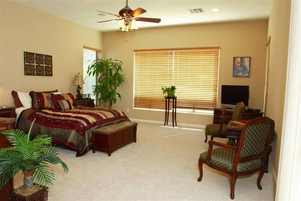 Spacious bedroom with a bed, chairs, and a TV.