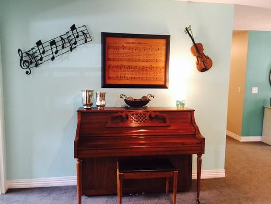 A wooden piano beside musical decor on the wall