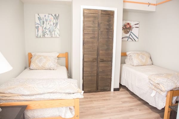 A shared bedroom featuring two wooden beds with patterned bedding and wall art.