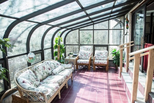 Sunroom with floral couches and greenery at Bea's Hive Assisted Living II.