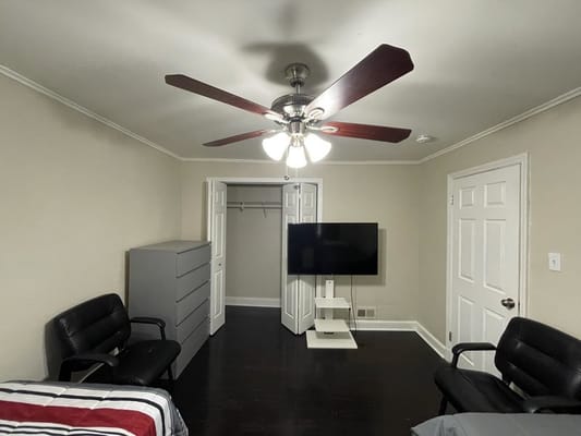 Interior view of a cozy bedroom with a ceiling fan and television.