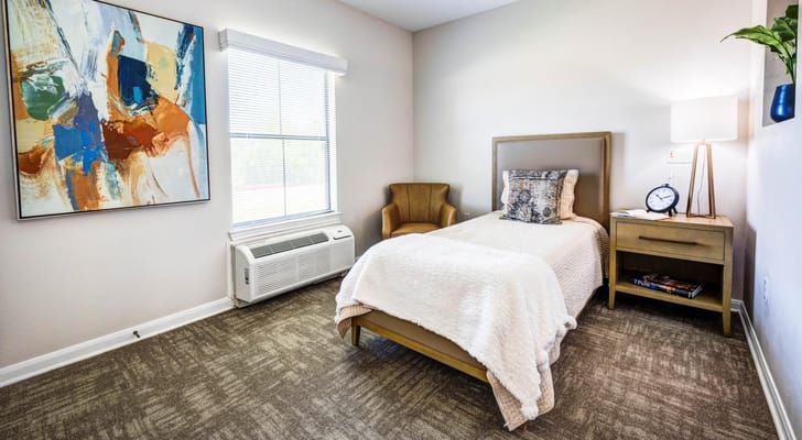 Cozy, well-lit resident room with a bed and chair
