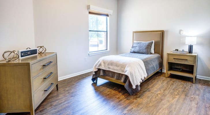 Well-decorated private resident room with bed and furniture