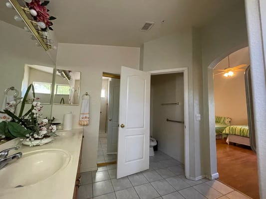 Well-lit bathroom with a view into an adjacent bedroom.