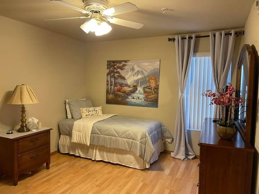 A well-furnished bedroom with a bed, lamp, and decorative wall art.
