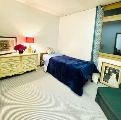 A cozy resident room with a bed and dresser