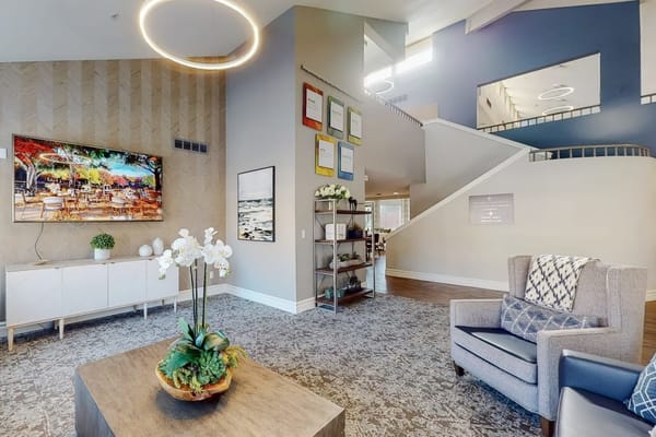 Bright lobby area with seating and decor, featuring a large TV and artwork.