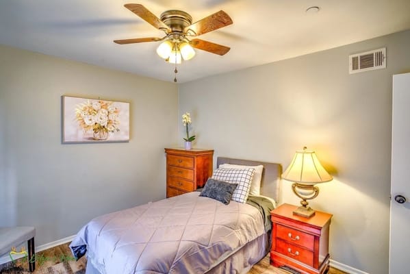 A cozy bedroom with a bed, lamp, and dresser.