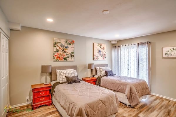 A cozy bedroom with two twin beds, decorative art, and natural light.