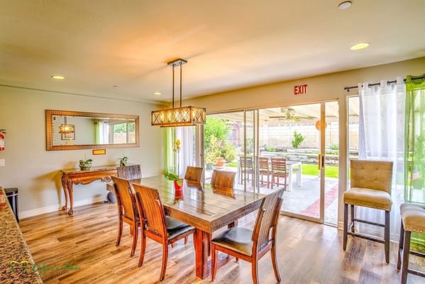 Bright dining area with a large wooden table and chairs, leading to an outdoor space.