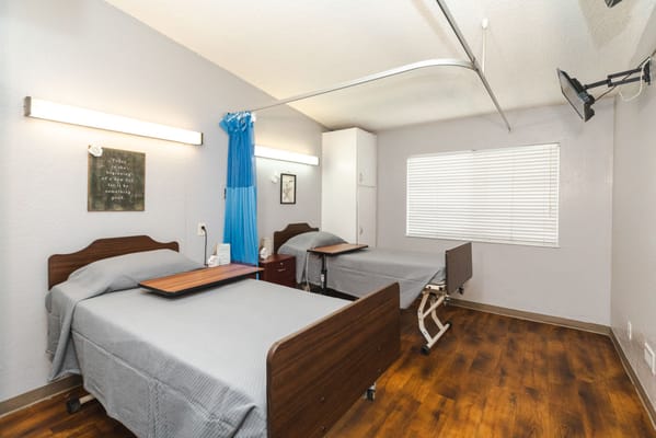 A well-lit interior of a shared resident room with two beds