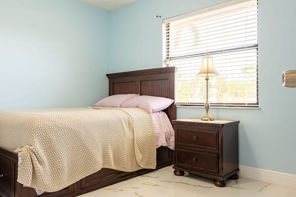 A well-lit bedroom with a bed and lamp.