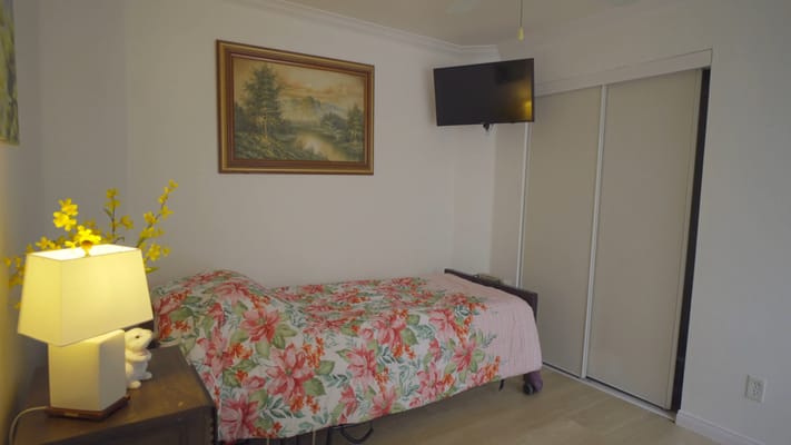 A cozy bedroom with floral bedding, lamp, and TV.