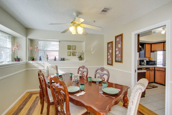 Well-lit dining room with a wooden table set for meals