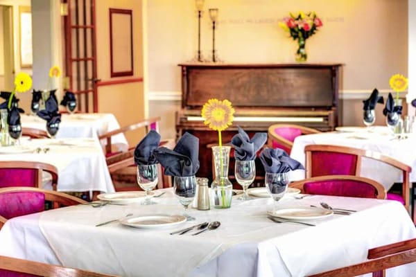 Elegant dining room setup with flowers and piano