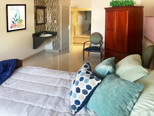 Cozy bedroom with a bed, colorful pillows, and a chair in the corner