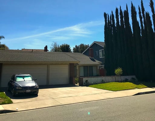 Front view of Joyful Home II with a parked car and tall trees