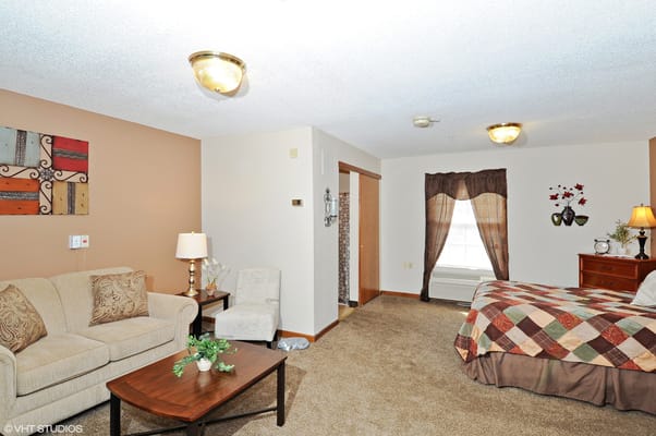 A cozy resident room featuring a bed and living area