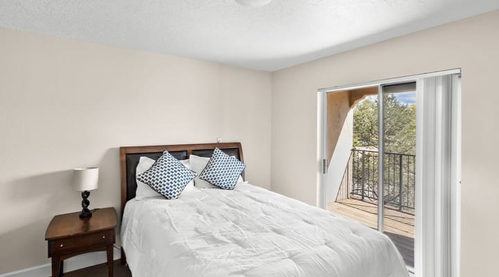 Bright bedroom with a queen bed and balcony access