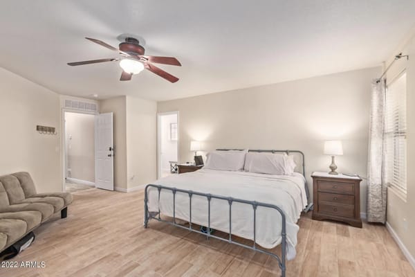 Bright bedroom with a double bed, nightstand, and a sofa.