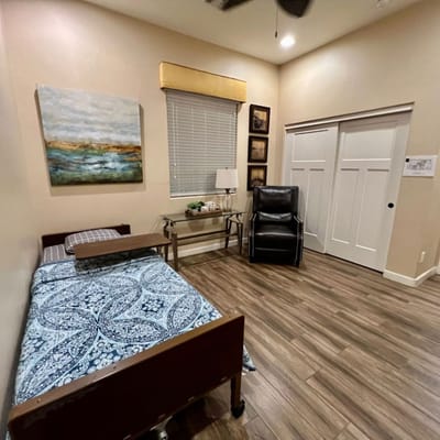 Comfortable bedroom featuring a bed, chair, and desk at Mulberry Assisted Living