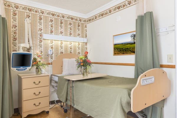 A comfortable room with a hospital bed, television, and floral decor