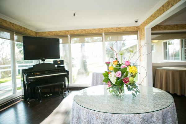 Bright common area featuring a grand piano and floral centerpiece
