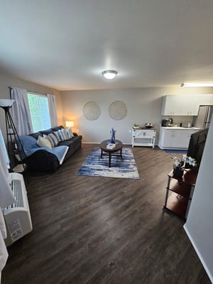 Bright living room with a couch, coffee table, and open kitchen area