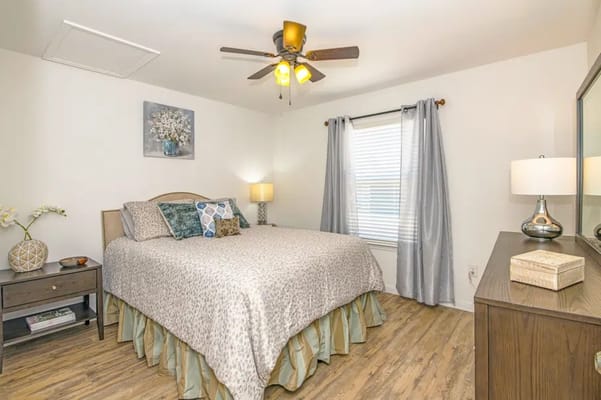 Bright bedroom with a queen bed, lamps, and curtains