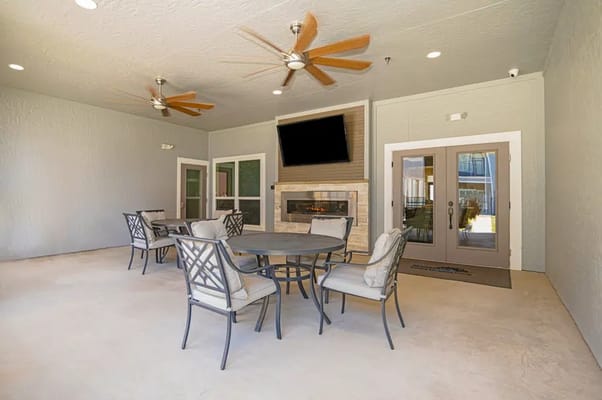 Outdoor seating area with a table and chairs, fireplace, and fans.