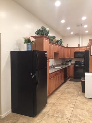 Interior view of kitchen with wooden cabinets and black refrigerator