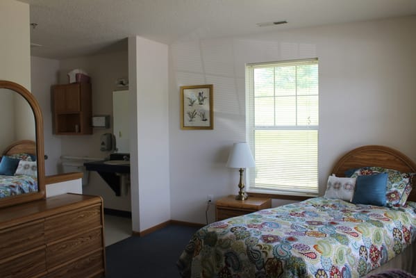 A well-furnished bedroom with a bed, lamp, and window.